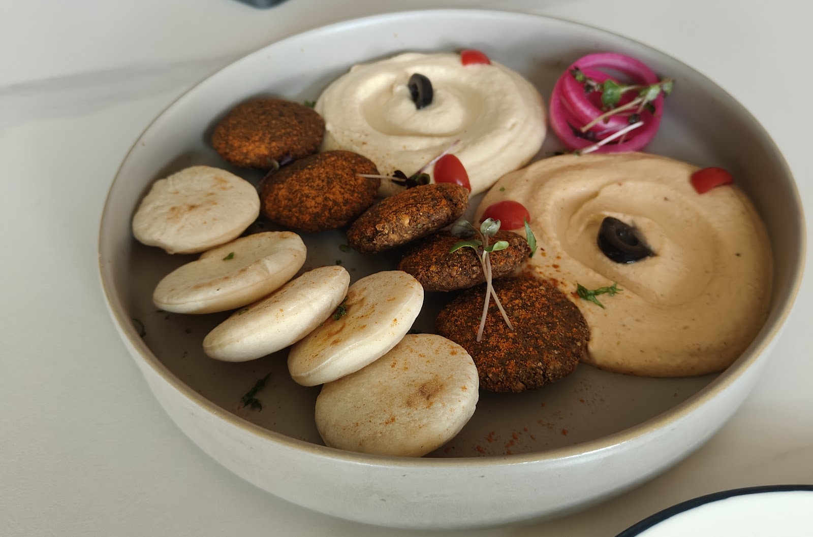 Podi idli and cutlets arranged around two chutneys in a wide bowl.
