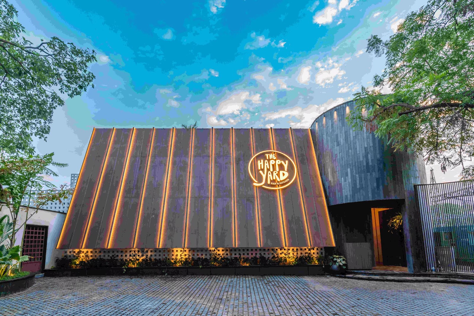 The slatted exterior wall lit gold at dusk, the circular logo at its centre.