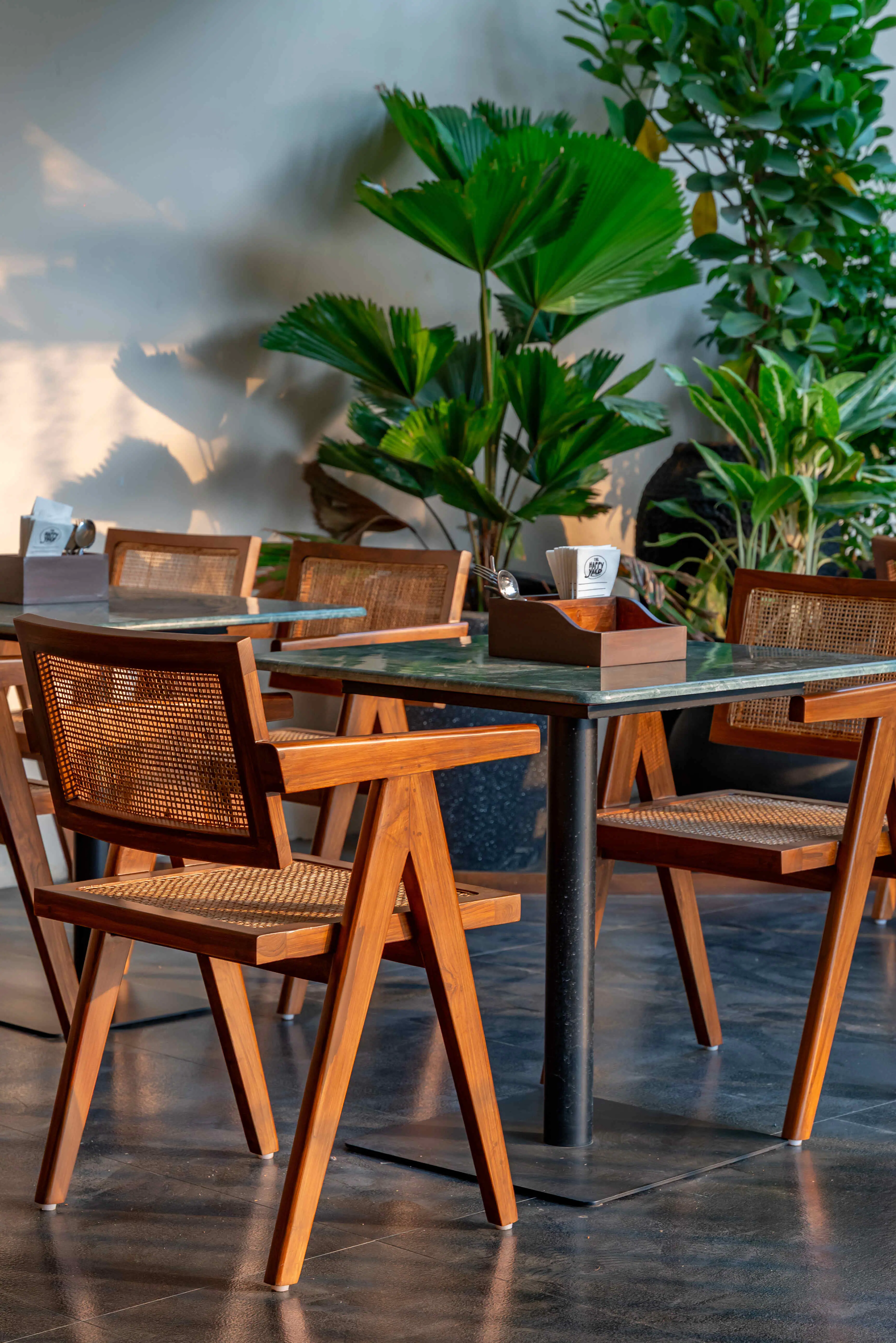 A cane-backed table for four beside a planted bed.