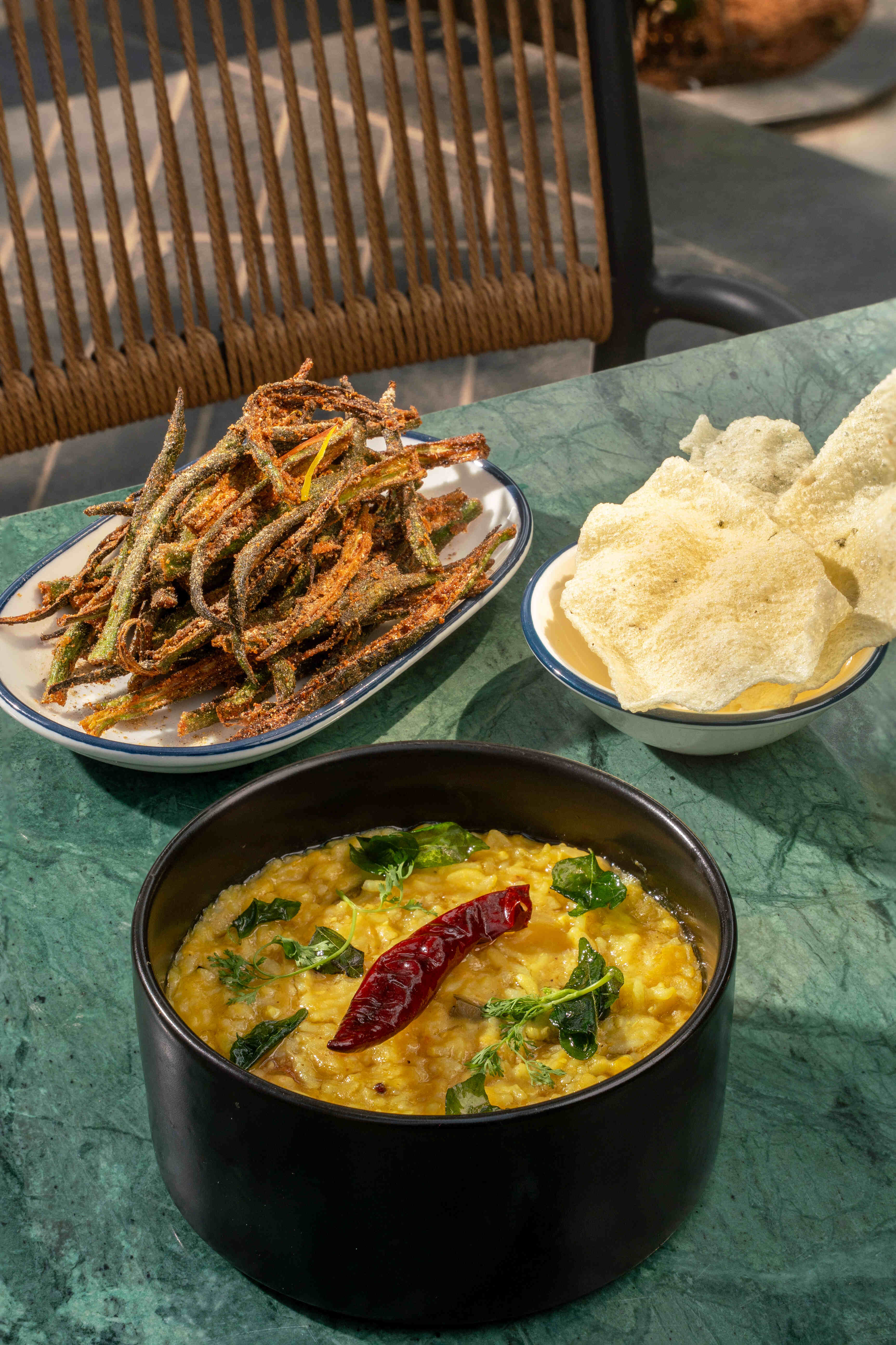 A dal with a dried chilli, crisp fried fish and papad alongside.